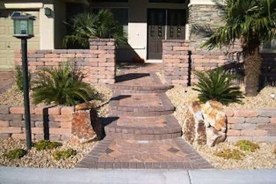 Design ideas for a mid-sized traditional drought-tolerant and full sun front yard stone retaining wall landscape in Las Vegas for summer.