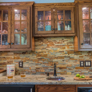 ミネアポリスの中サイズのトラディショナルスタイルのおしゃれなウェットバー (シンクなし、落し込みパネル扉のキャビネット、中間色木目調キャビネット、御影石カウンター、マルチカラーのキッチンパネル、石タイルのキッチンパネル、コルクフローリング、茶色い床) の写真