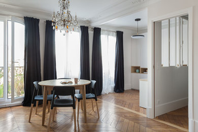 This is an example of a mid-sized scandinavian dining room in Paris with light hardwood floors and a standard fireplace.