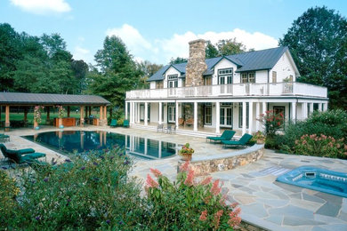 Example of a large classic backyard stone and rectangular infinity hot tub design in Other