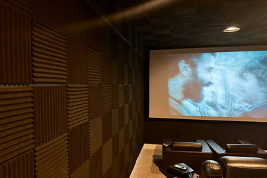 Example of a huge classic enclosed home theater design in DC Metro with black walls and a projector screen
