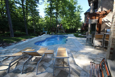 Photo of a mid-sized transitional backyard custom-shaped pool in Chicago with brick pavers.