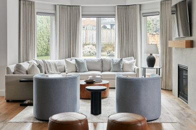 Example of a mid-sized transitional open concept medium tone wood floor and brown floor living room design in Toronto with white walls, a standard fireplace and a wall-mounted tv
