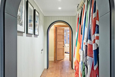 Photo of a medium sized contemporary hallway in Cornwall with a single front door, a glass front door, panelled walls, a feature wall, grey walls, dark hardwood flooring and brown floors.