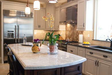 Eat-in kitchen - mediterranean l-shaped ceramic tile and beige floor eat-in kitchen idea in Other with a double-bowl sink, recessed-panel cabinets, beige cabinets, soapstone countertops, beige backsplash, glass tile backsplash, stainless steel appliances and an island