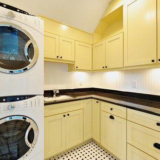 This is an example of a traditional utility room in Philadelphia with a stacked washer and dryer and multi-coloured floors.