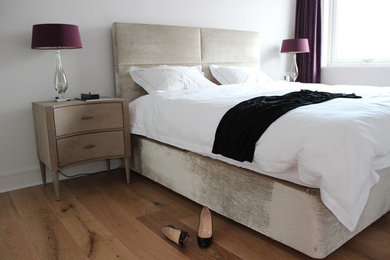 Design ideas for a mid-sized contemporary master bedroom in London with white walls and medium hardwood floors.