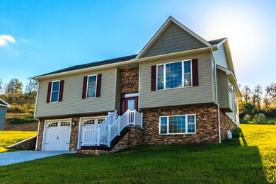 Large transitional gray two-story stone exterior home idea in Other with a clipped gable roof