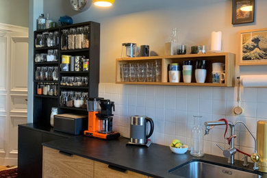 ベルリンにある低価格の小さなコンテンポラリースタイルのおしゃれなキッチン (中間色木目調キャビネット、ライムストーンカウンター、アイランドなし、黒いキッチンカウンター) の写真