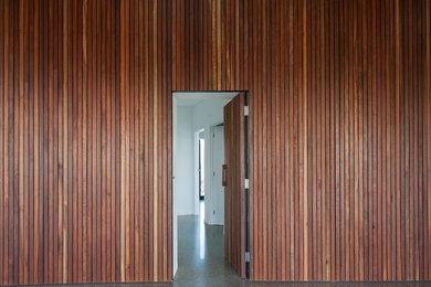 Inspiration for a mid-sized modern hallway in Melbourne with brown walls and concrete floors.