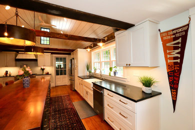 Eat-in kitchen - huge farmhouse l-shaped medium tone wood floor, brown floor and shiplap ceiling eat-in kitchen idea in Boston with a farmhouse sink, shaker cabinets, white cabinets, soapstone countertops, stainless steel appliances, an island and black countertops