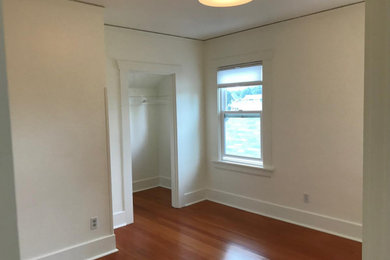 シアトルにある中くらいなトラディショナルスタイルのおしゃれな客用寝室 (白い壁、無垢フローリング、赤い床) のインテリア