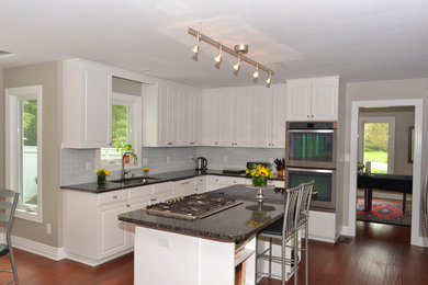 Eat-in kitchen - contemporary u-shaped bamboo floor eat-in kitchen idea in Other with a single-bowl sink, raised-panel cabinets, white cabinets, granite countertops, white backsplash, glass tile backsplash, stainless steel appliances and an island