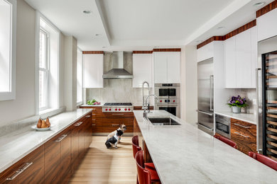 Design ideas for a mid-sized contemporary u-shaped kitchen in Boston with an undermount sink, flat-panel cabinets, white cabinets, quartz benchtops, stainless steel appliances, with island, grey splashback, light hardwood floors and beige floor.