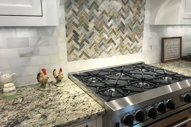 Kitchen - mid-sized transitional kitchen idea in Other with granite countertops, a farmhouse sink, white cabinets, marble backsplash, stainless steel appliances, an island and recessed-panel cabinets