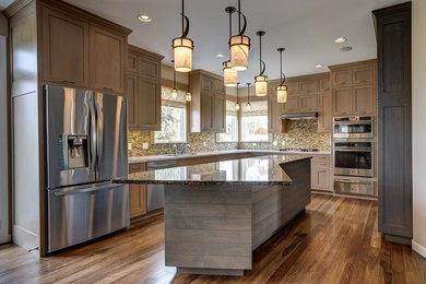 Inspiration for a mid-sized rustic u-shaped light wood floor enclosed kitchen remodel in Burlington with a drop-in sink, shaker cabinets, medium tone wood cabinets, quartz countertops, multicolored backsplash, glass tile backsplash, stainless steel appliances and an island