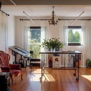 Design ideas for a traditional home studio in Seattle with white walls, medium hardwood floors, a wood stove, a brick fireplace surround, a freestanding desk and brown floor.