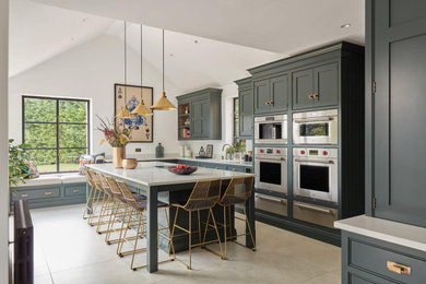 Large bohemian kitchen in Kent with shaker cabinets, green cabinets, quartz worktops, stainless steel appliances and an island.