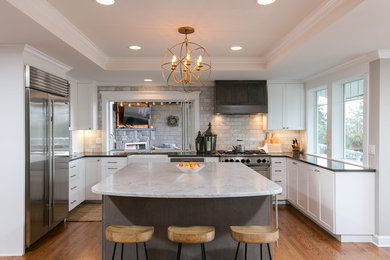 Kitchen - transitional u-shaped medium tone wood floor and brown floor kitchen idea in Seattle with a farmhouse sink, shaker cabinets, white cabinets, marble countertops, gray backsplash, subway tile backsplash, stainless steel appliances, an island and gray countertops