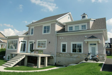 Elegant beige three-story wood and shingle house exterior photo in Montreal with a shingle roof and a gray roof