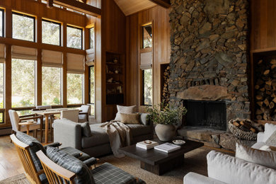 Country living room in Sacramento with brown walls, dark hardwood floors, a stone fireplace surround, no tv, brown floor, vaulted, wood and wood walls.