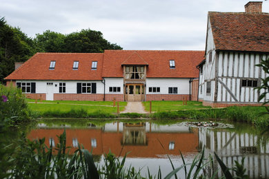 Large arts and crafts two-storey stucco white house exterior in Hertfordshire with a gable roof and a tile roof.