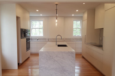 Mid-sized minimalist kitchen photo with flat-panel cabinets, white cabinets, white backsplash and white countertops