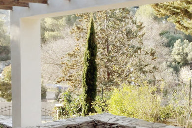 Ejemplo de patio mediterráneo de tamaño medio en patio delantero con jardín vertical, adoquines de piedra natural y pérgola
