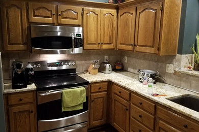 Eat-in kitchen - mid-sized modern l-shaped dark wood floor eat-in kitchen idea in Kansas City with an undermount sink, raised-panel cabinets, brown cabinets, granite countertops, beige backsplash, ceramic backsplash, stainless steel appliances and no island