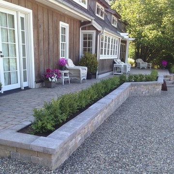 new stone paver patio added along house with planters and steps