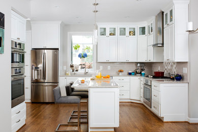 Kitchen - mid-sized transitional l-shaped medium tone wood floor kitchen idea in DC Metro with white cabinets, beige backsplash, subway tile backsplash, stainless steel appliances and an island