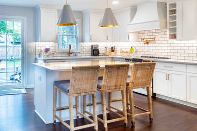 Inspiration for a mid-sized transitional l-shaped eat-in kitchen in Cleveland with an undermount sink, shaker cabinets, white cabinets, quartz benchtops, white splashback, subway tile splashback, stainless steel appliances, light hardwood floors, with island, brown floor and white benchtop.
