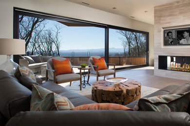 Example of a large trendy enclosed light wood floor living room design in Other with gray walls, a stone fireplace and a media wall