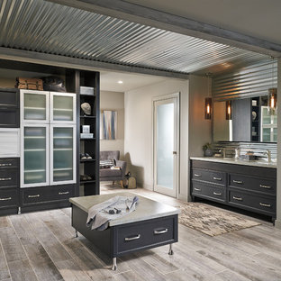 Cette photo montre une grande douche en alcôve principale industrielle avec un placard à porte shaker, des portes de placard en bois sombre, un carrelage gris, carrelage en métal, un mur beige, un sol en bois clair, un lavabo encastré, un plan de toilette en quartz, un sol beige, une cabine de douche à porte battante et un plan de toilette beige.