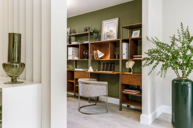 This is an example of a large contemporary home office in Other with green walls, light hardwood flooring and a freestanding desk.