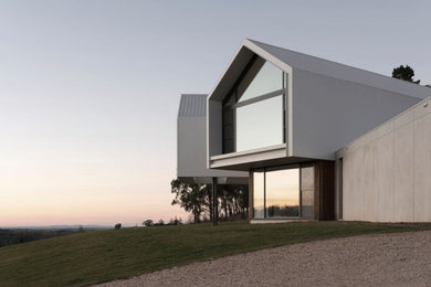 Large modern two-storey white house exterior in Other with wood siding, a gable roof, a metal roof and a white roof.