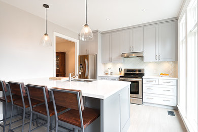 Inspiration for a mid-sized transitional galley ceramic tile enclosed kitchen remodel in Toronto with an undermount sink, recessed-panel cabinets, gray cabinets, marble countertops, glass tile backsplash, stainless steel appliances and an island