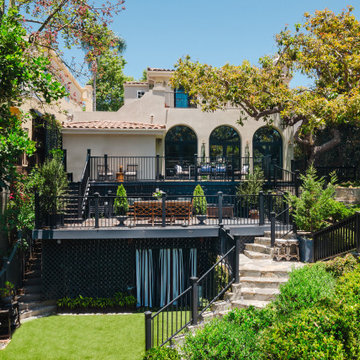 Mediterranean Backyard with Multi-Level Deck, Arched Doors, and Lush Landscaping