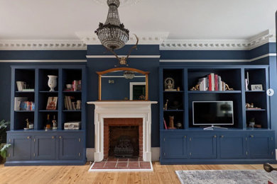 Large victorian living room in London with blue walls and a built-in media unit.