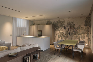 Immagine di una sala da pranzo aperta verso la cucina moderna con pareti verdi, parquet chiaro, pavimento marrone e carta da parati