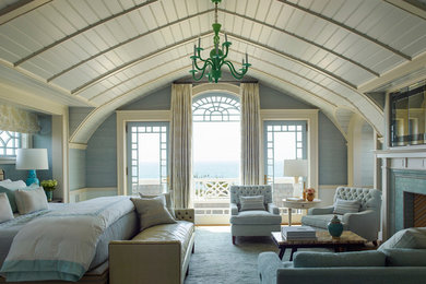 This is an example of a large beach style master bedroom in New York with blue walls, carpet, a standard fireplace, a tile fireplace surround and white floor.