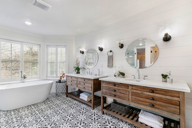 Mid-sized transitional master bathroom in Sacramento with furniture-like cabinets, distressed cabinets, a freestanding tub, a corner shower, white tile, ceramic floors, an undermount sink, engineered quartz benchtops, black floor, a hinged shower door and white benchtops.