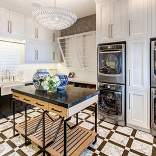 ソルトレイクシティの巨大なトランジショナルスタイルのおしゃれな洗濯室 (エプロンフロントシンク、落し込みパネル扉のキャビネット、グレーの壁、上下配置の洗濯機・乾燥機、白い床、白いキッチンカウンター、白いキャビネット) の写真