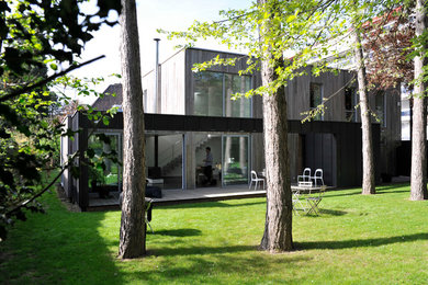 Cette image montre une grande façade de maison marron design en bois à un étage avec un toit plat.