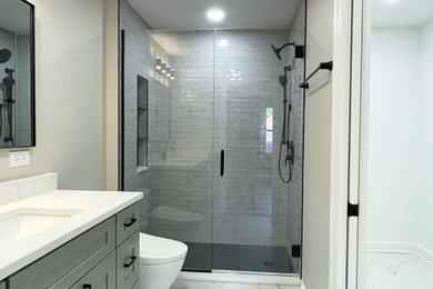 Mid-sized minimalist master gray tile and porcelain tile single-sink bathroom photo in Chicago with shaker cabinets, green cabinets, a one-piece toilet, an undermount sink, quartz countertops, white countertops and a built-in vanity