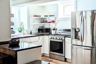 Inspiration for a laminate floor and brown floor kitchen remodel in Minneapolis with a double-bowl sink, white cabinets, granite countertops, stainless steel appliances and multicolored countertops