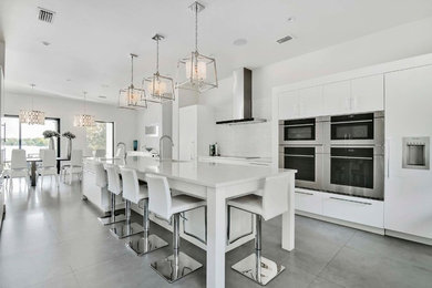 Inspiration for a large modern galley eat-in kitchen in Orlando with an undermount sink, flat-panel cabinets, white cabinets, quartz benchtops, white splashback, stone tile splashback, panelled appliances, porcelain floors and with island.