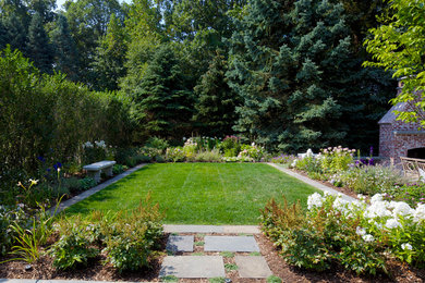 This is an example of a large country side yard partial sun formal garden in New York with a fire feature and natural stone pavers.