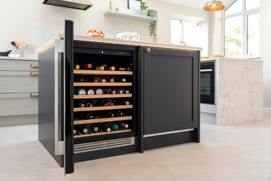 Inspiration for a large contemporary galley kitchen/diner in West Midlands with a built-in sink, shaker cabinets, grey cabinets, marble worktops, black appliances, ceramic flooring, an island, white floors and white worktops.