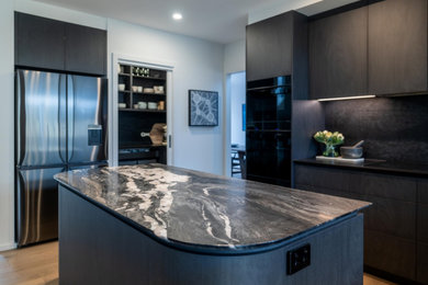 Mid-sized contemporary kitchen in Melbourne with marble benchtops, black splashback, engineered quartz splashback and black appliances.